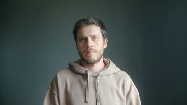 Puzzled caucasian man shrugging shoulders with confused facial expression, showing doubt and uncertainty while gesturing with hands, looking directly at camera. Young man shrugging shoulders indoors