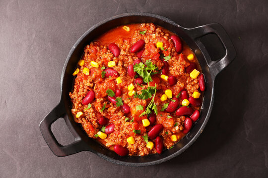 Chili con carne with minced beef beans and corn in black pan