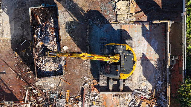 Aerial Top Down View of Yellow Excavator Loading Demolition Debris
