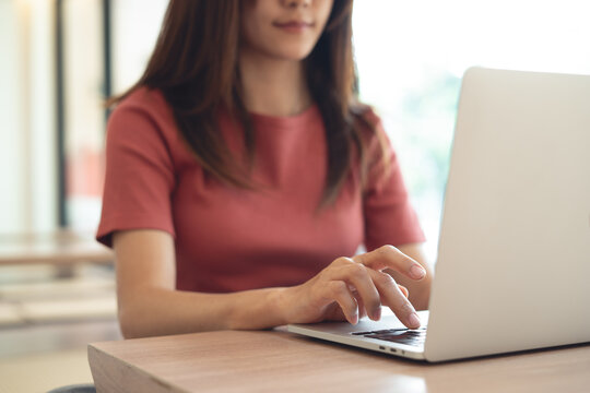 Young asian woman working remotely, using laptop  surfing the net at cafe modern workspace. online job, freelance at work, business casual. 