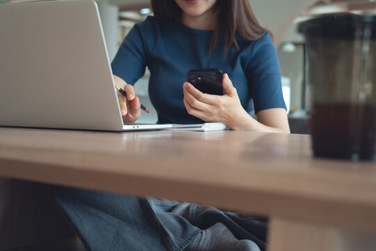 Young asian woman sitting on the floor, using laptop and smartphone, online working at home. remote work, digital nomad lifestyle, business casual concept