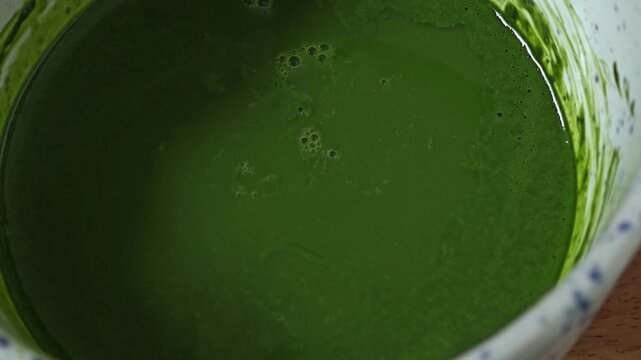 Matcha in bowl with bamboo whisk.