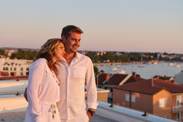Obraz premium Romantic Couple On Rooftop Balcony At Sunset With Sea View Over Umag Harbor