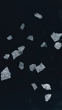 Floating silver fragments in dark background