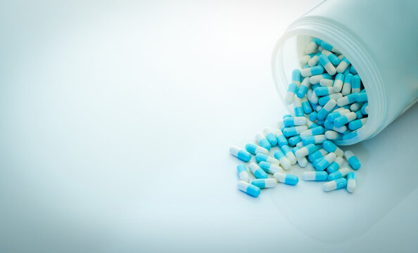 Blue-white antibiotic capsule pill and capsule pills bottle. Antibiotic drug resistance. Pharmaceutics concept. Pharmaceutical industry. Pharmacy product. Capsule pills production. Antimicrobial drug.