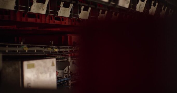 Automated conveyor system moving red plastic crates through a dark industrial hall with metal guides