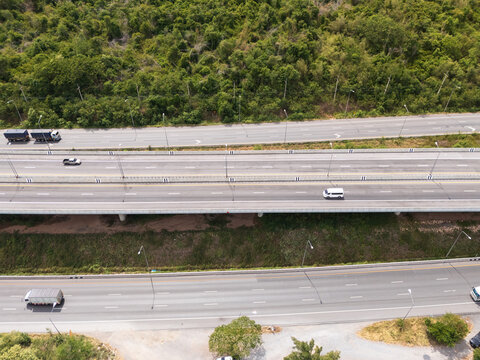 Drone aerial view of an elevated highway crossing lush forest and mountain landscape under dramatic clouds, The modern transportation infrastructure and nature concept