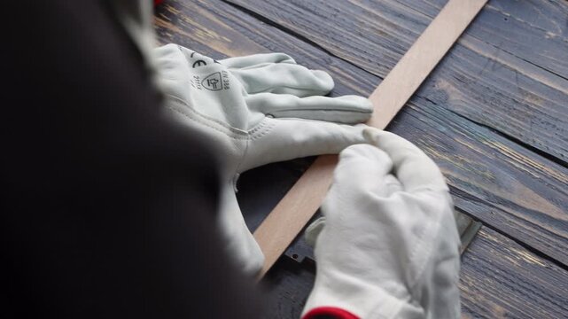 Worker hands in white safety gloves measuring metal plate on workshop bench
