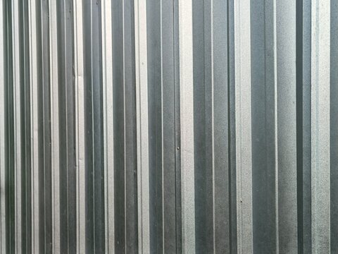 Detailed view of corrugated metal sheet or zinc cladding, capturing the textured silver surface and rhythmic ridges through.