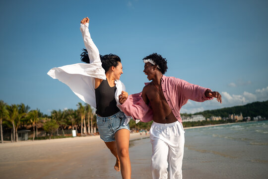 Happy couple having fun at the beach, playing and laughing together in a romantic tropical setting