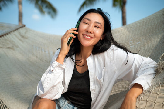 Happy woman celebrating freedom holding white shirt in the wind against blue sky at tropical beach