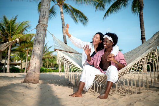 Diverse content creator couple vlogging or streaming from a scenic tropical beach on summer vacation