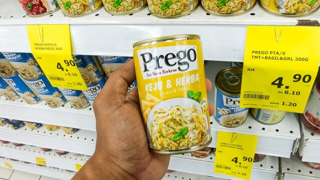 Malaysia Kuala Terengganu 18 July 2026: Hand holding a can of Prego traditional tomato pasta sauce product close up on a grocery store shelf background.