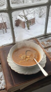Bowl of soup on windowsill overlooking snowy yard