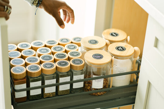 Hand reaching for spice in an organized kitchen drawer