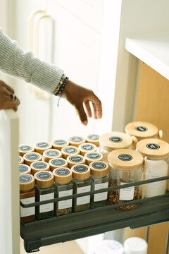 Black person organizing spices in kitchen pantry