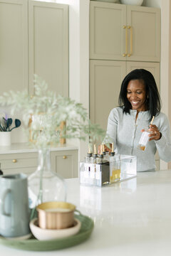 Smiling black woman organizing bottles in her kitchen