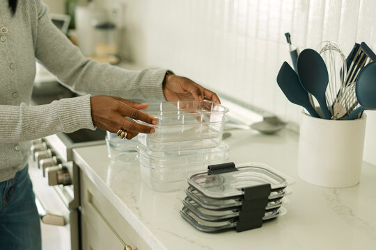 Woman stacking clear food storage containers in kitchen