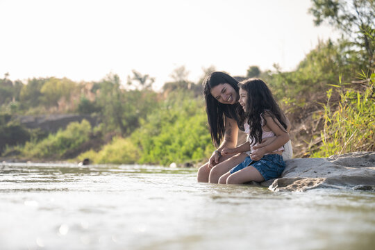 Happy mother and daughter laughing together by the river