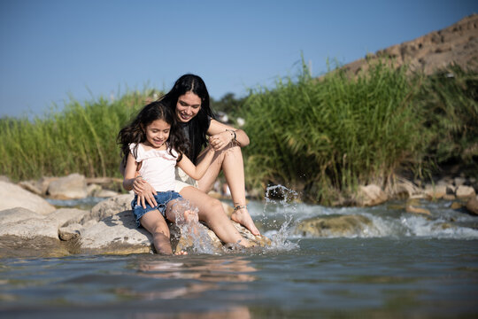 Happy mother and daughter splashing in river together