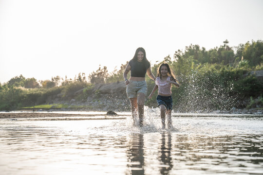 Happy mother and daughter running through a river