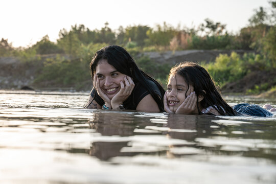 Happy mother and daughter relaxing in river water