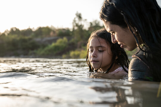 Mother and daughter bonding in a river at sunset