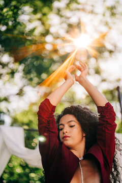 Woman with dark curly hair dancing in the sunlight