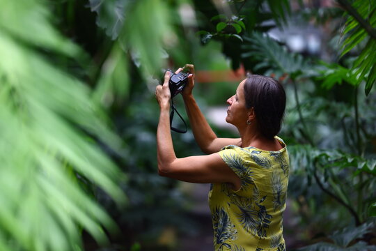 Female traveler photographing tropical plants in botanical garden
