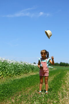 Young girl tossing her sun hat in a wildflower meadow