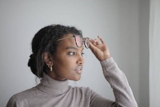 Black woman thoughtfully pushes her glasses up