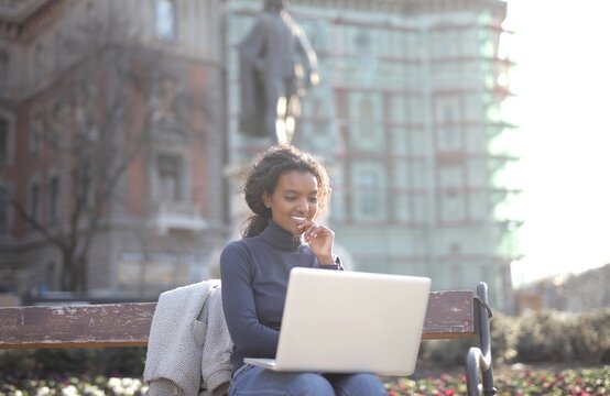Smiling woman working on her laptop outdoors