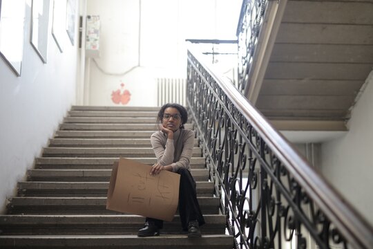 Young black woman holding cardboard sign on stairs