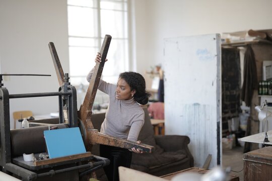 Young black woman operating a vintage printing press