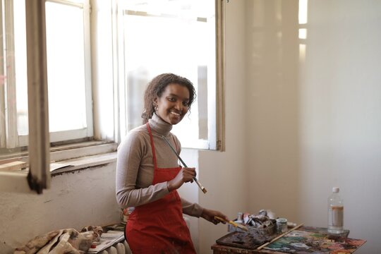 Happy young Black woman painting in art studio