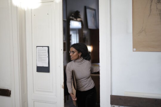 Young black woman with glasses looking back in doorway