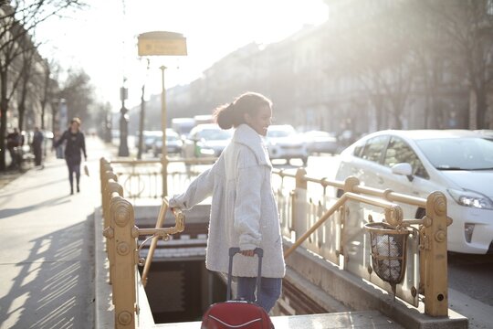Smiling woman with luggage enters city subway station