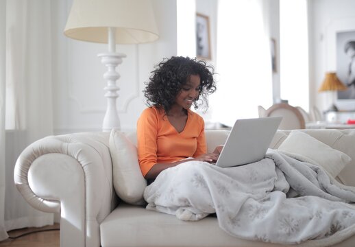 Smiling young woman typing on her laptop at home