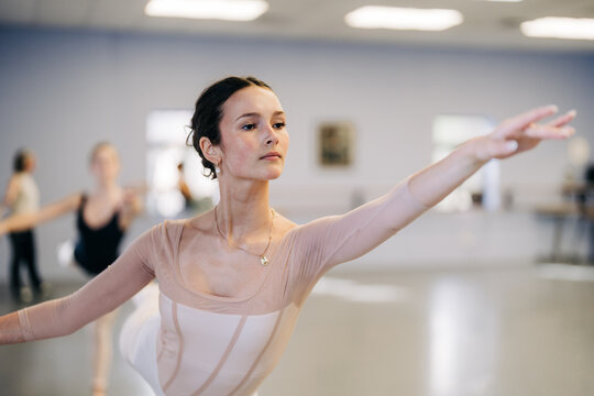 Young ballerina practicing elegant ballet pose in dance studio