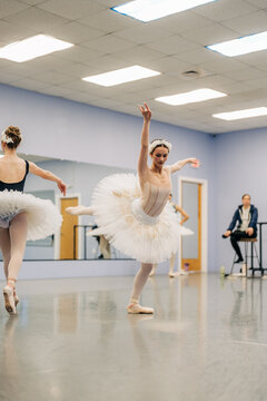 Young ballerina rehearsing arabesque with classmates in dance studio