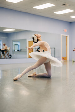 Young ballerina performing expressive floor pose in ballet studio