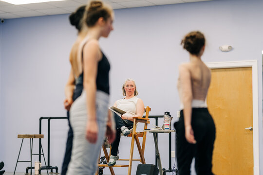 Dance instructor coaching young ballerinas during a studio rehearsal
