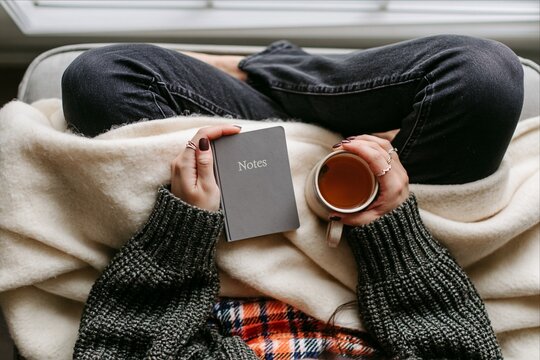 Overhead view of woman relaxing with tea and notebook