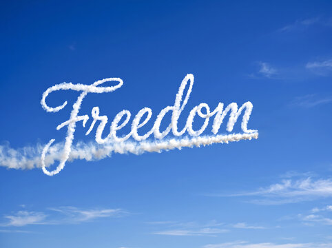 White skywriting of freedom word formed by smoke trails in clear blue sky background for concept of liberty peace and independence day celebration with fluffy clouds below text as artistic message.