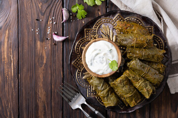 Delicious dolma (sarma), dolmades stuffed grape leaves rice, white yogurt sauce. Mediterranean Dolma. Lebanon turkish greek middle eastern cuisine. View from above. Copy space. © elena_hramowa
