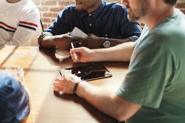 Fototapeta na wymiar Diverse men in a meeting around a table, discussing with a tablet and notepad