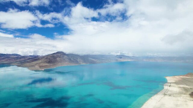 Drone view of Pegu Tso lake or Peikucuo in sunny day in Shigatse, Tibet, China, beautiful peaceful turquoise sea with mountains reflections in Xizang, 4k real time footage travel concept