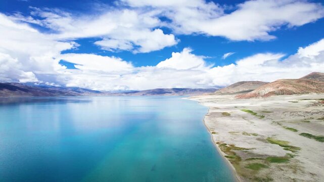 Drone view of Pegu Tso lake or Peikucuo in sunny day in Shigatse, Tibet, China, beautiful peaceful turquoise sea with mountains reflections in Xizang, 4k real time footage travel concept