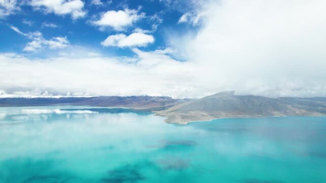 Drone view of Pegu Tso lake or Peikucuo in sunny day in Shigatse, Tibet, China, beautiful peaceful turquoise sea with mountains reflections in Xizang, 4k real time footage travel concept