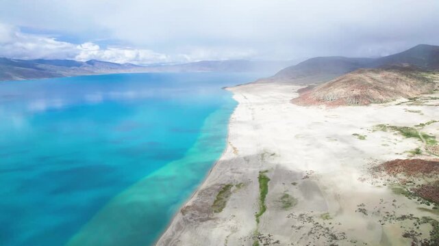 Drone view of Pegu Tso lake or Peikucuo in sunny day in Shigatse, Tibet, China, beautiful peaceful turquoise sea with mountains reflections in Xizang, 4k real time footage travel concept